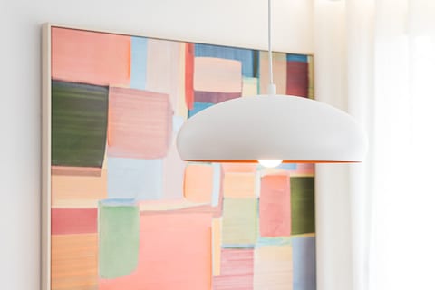 Modern pendant lighting and bold abstract art in a bright, airy setting