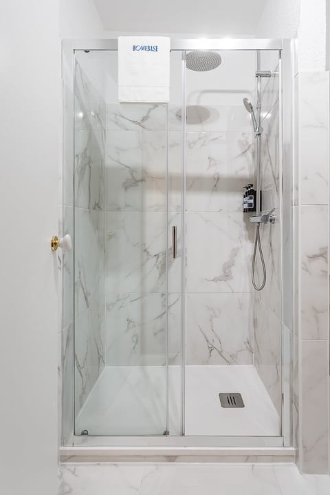 Spa-like marble walk-in shower with rain head, handheld, and toiletries.