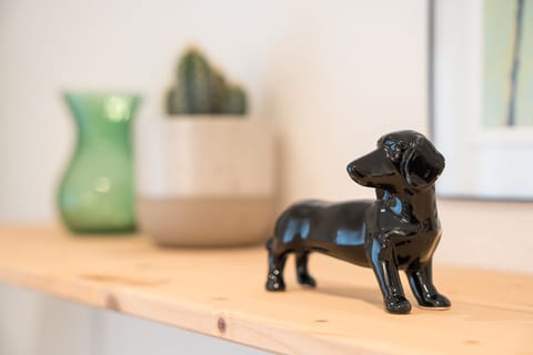 Chic accents: ceramic pup, greenery, and art on a sleek wood shelf