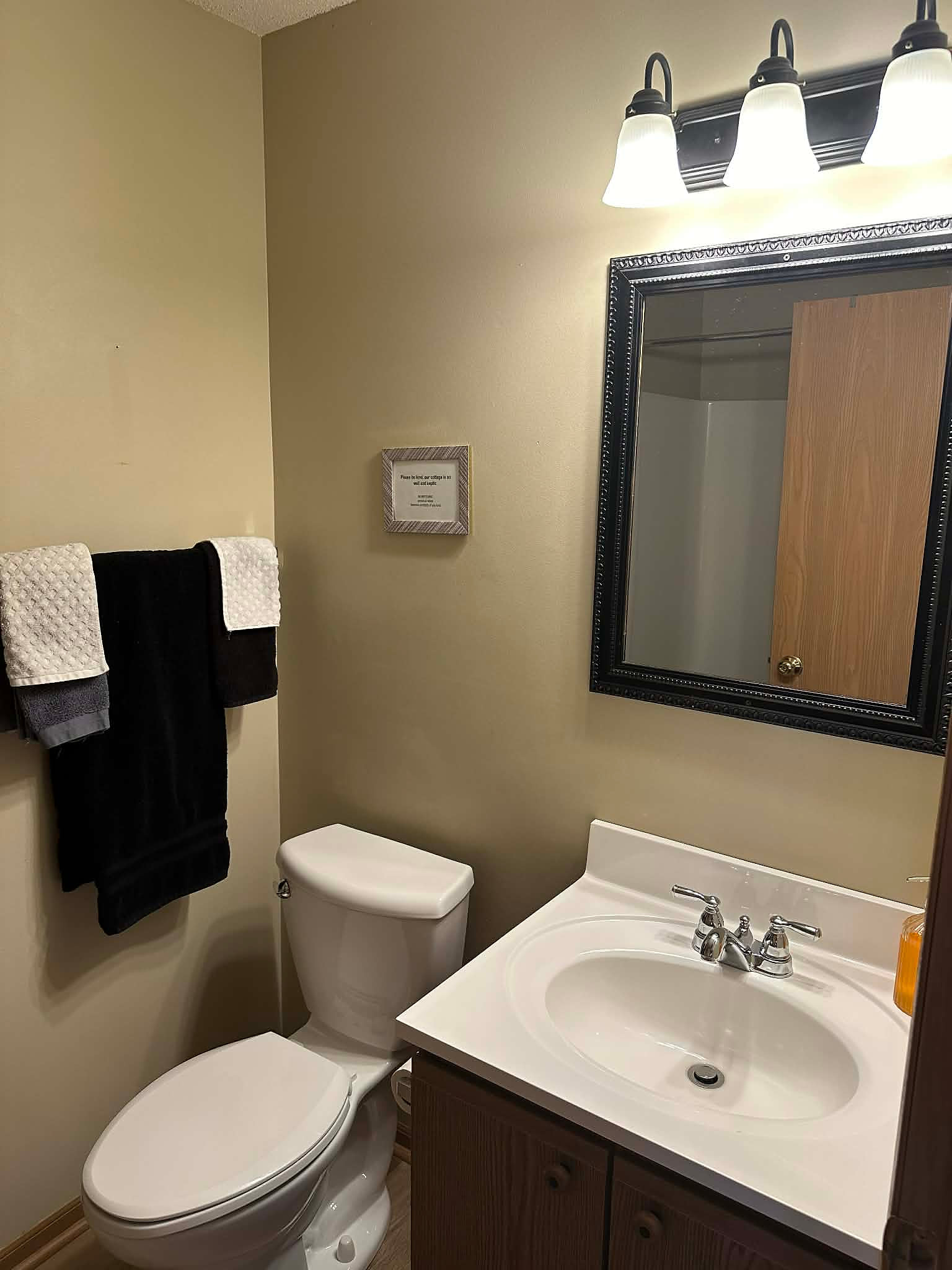 Spotless half-bath with fresh towels, bright lighting, and essentials.