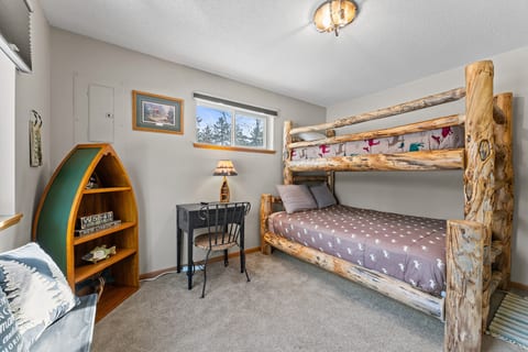Rustic bunk room with log beds, cozy desk, and charming cabin style