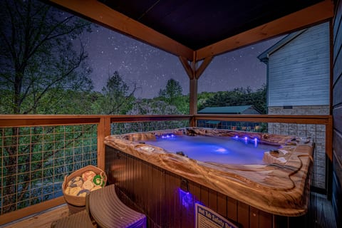 Private covered deck with LED-lit hot tub and forest views.