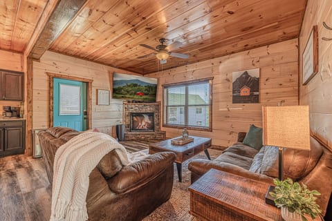 Cozy wood-paneled cabin living room with fireplace & leather sofas