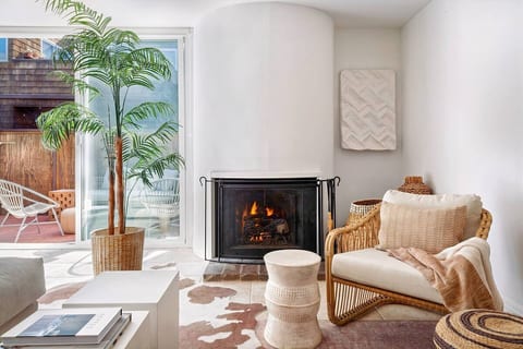 Relax and unwind in this beautiful light-filled living space featuring floor-to-ceiling windows, a round gas fireplace, beautifully appointed furniture and lush pillows and throws.