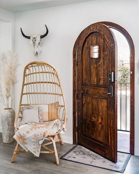 The rattan chair is a great spot to curl up with a book.  

The hand-crafted front door was made from a solid piece of wood, its accents match the Spanish style of the exterior of the home.  
