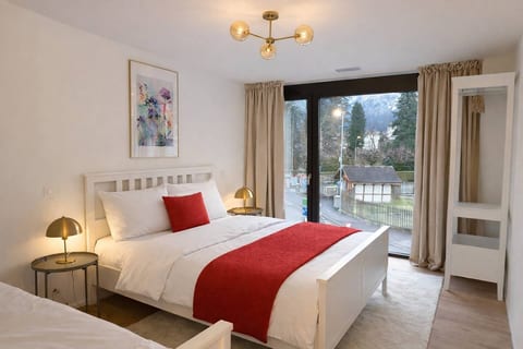 A spacious master bedroom with a comfortable double bed, bedside lamps, and large windows overlooking the surroundings.
