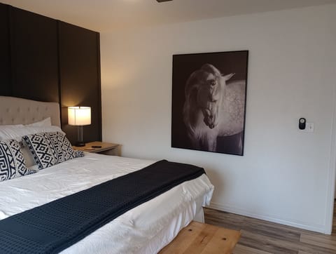 Chic king bedroom with bold accent wall, plush bedding, and modern art. Sleep your best sleep in this gorgeous primary bedroom with crisp clean sheet, room darkening shades, Smart TV, and ensuite bathroom. Sliding glass doors lead out to the back deck.