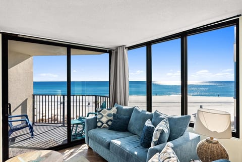 Gulf-front living room with floor-to-ceiling windows and direct balcony access.