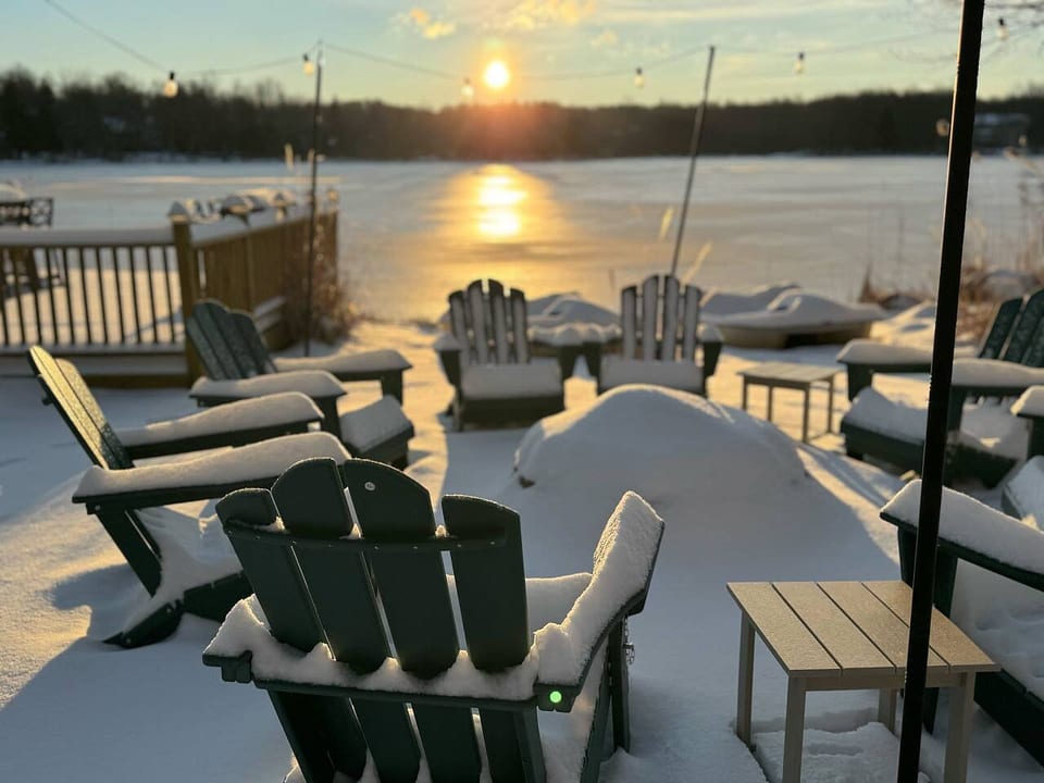 Cozy up by the firepit, surrounded by snow, with the frozen lake stretching out before you — a perfect winter escape.
