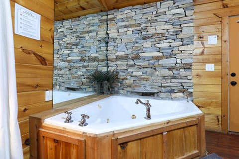 Rustic jetted tub with stone accent wall—your private cabin spa