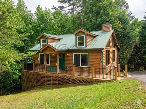 Charming log cabin with green roof, wraparound deck & forest views