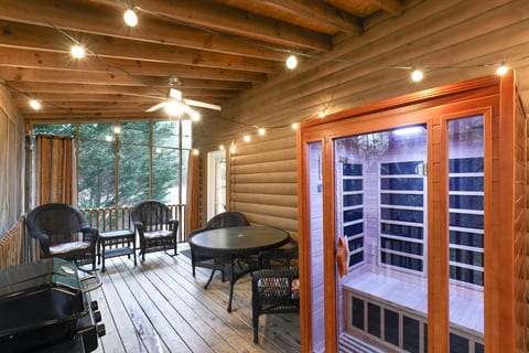 Screened porch with sauna, grill & cozy seating under twinkle lights.