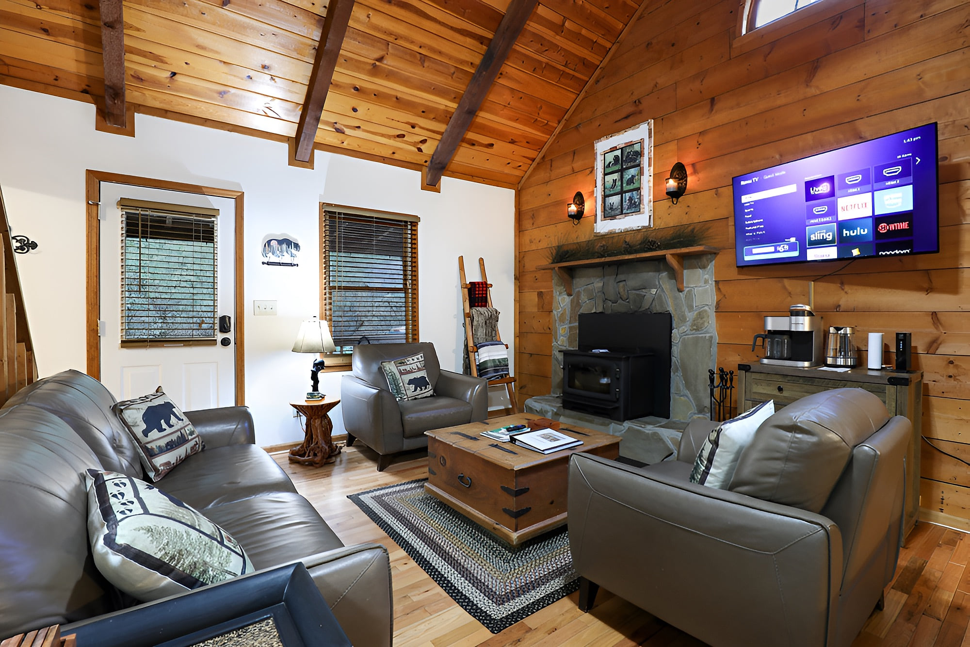 Cozy cabin lounge with fireplace, smart TV, leather sofas & coffee bar.