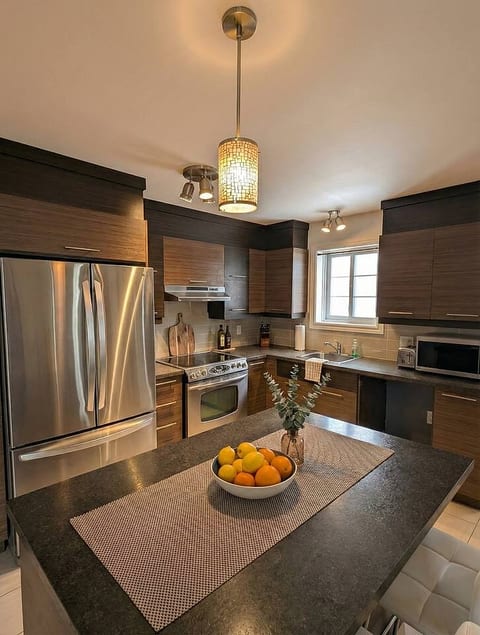 Cook in style in this modern, fully equipped kitchen. Features stainless steel appliances, dark wood cabinetry, and a large island perfect for gathering and prepping meals.
