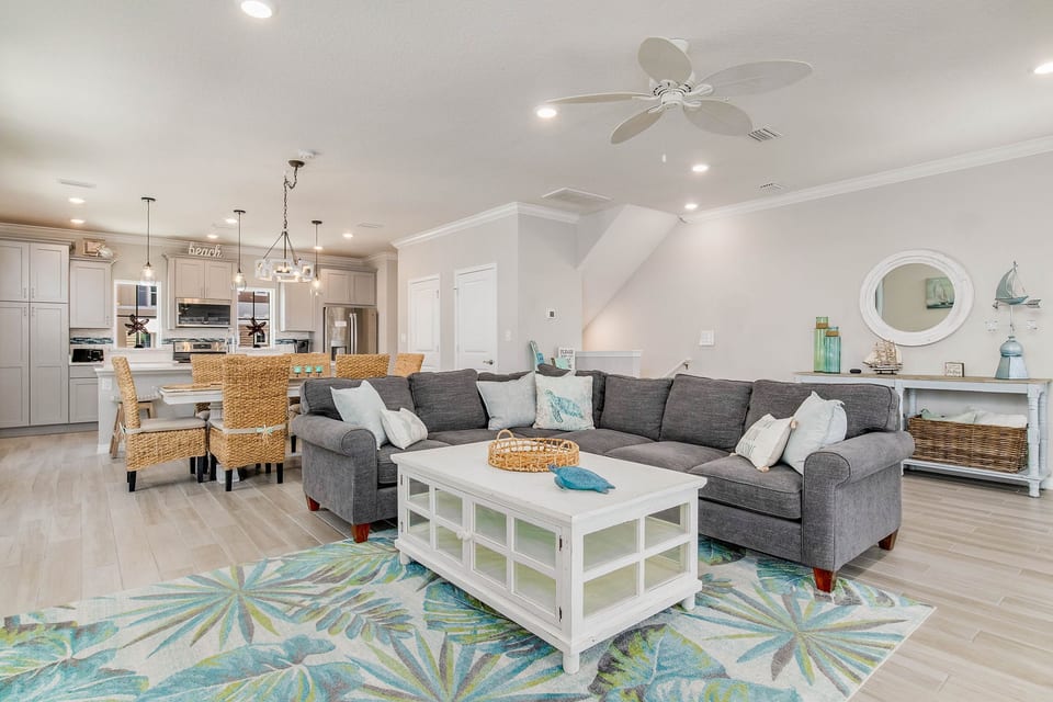 Open-concept living room with L-shaped sectional and balcony access at Lost Key townhome