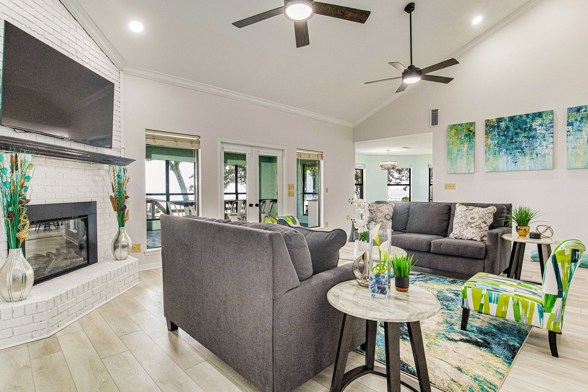 Open-concept living room with white brick fireplace and bay views at Gulf Breeze waterfront house near Pensacola
