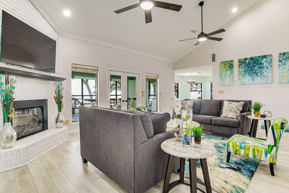 Open-concept living room with white brick fireplace and bay views at Gulf Breeze waterfront house near Pensacola
