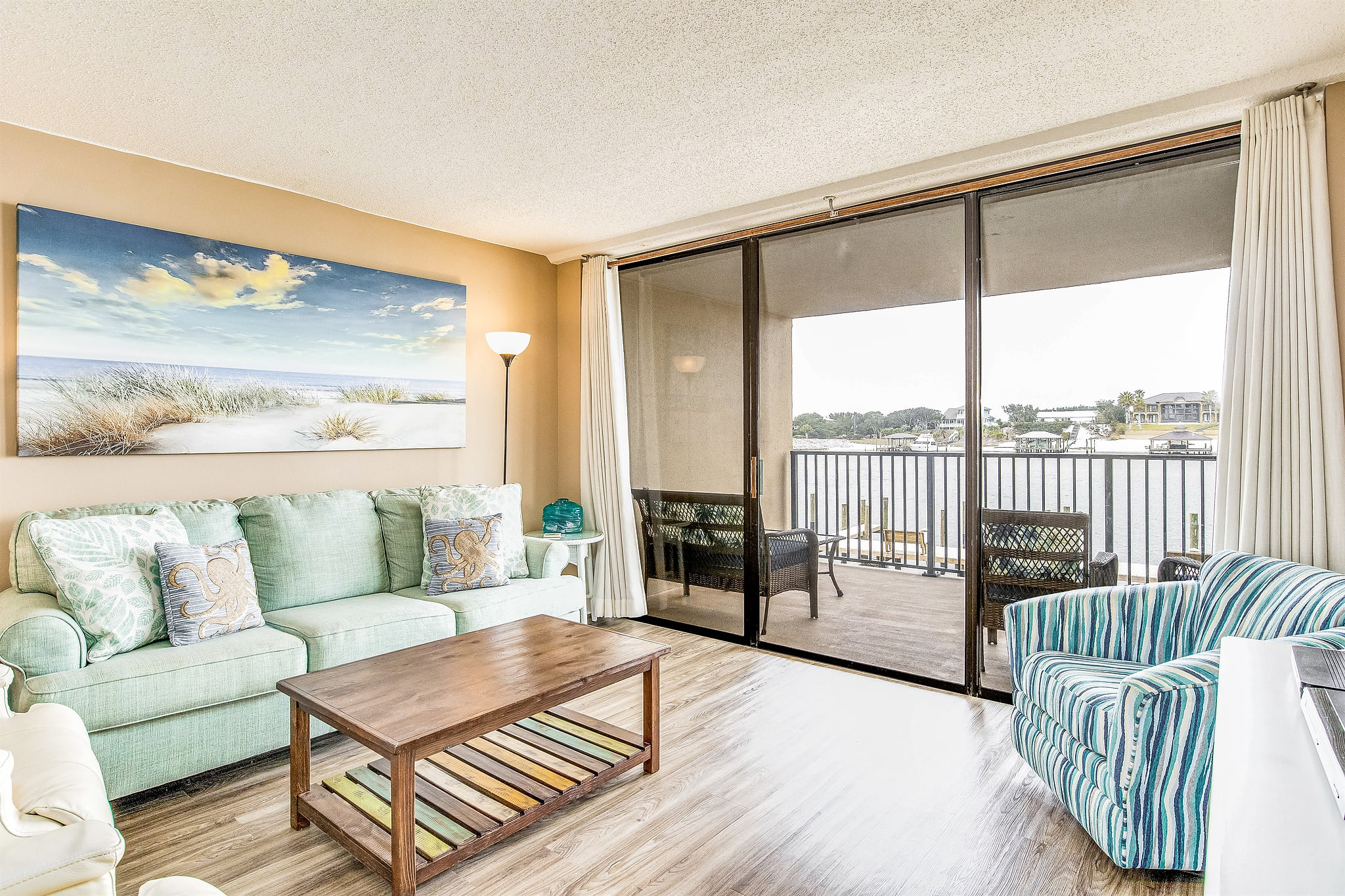 Coastal-inspired living area with flat-screen TV and sliding glass doors to covered balcony overlooking Old River Orange Beach