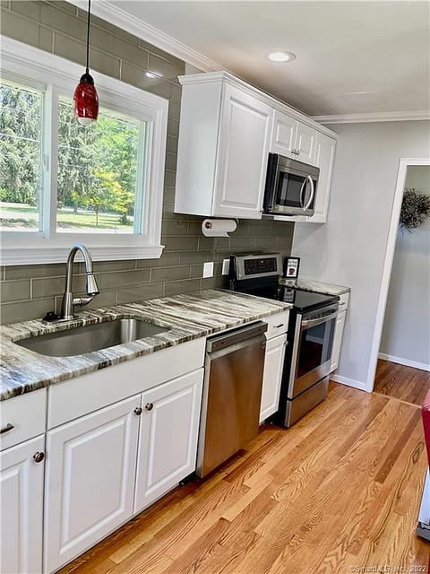 Bright modern kitchen with stainless appliances and stone countertops.