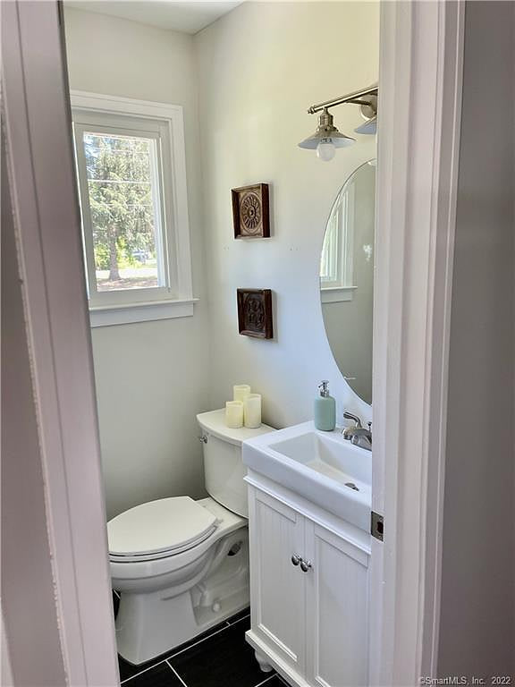 Bright, modern half-bath with window, sleek vanity, and black tile floor.
