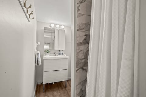 Bright, modern bath with marble-tile shower and sleek storage vanity