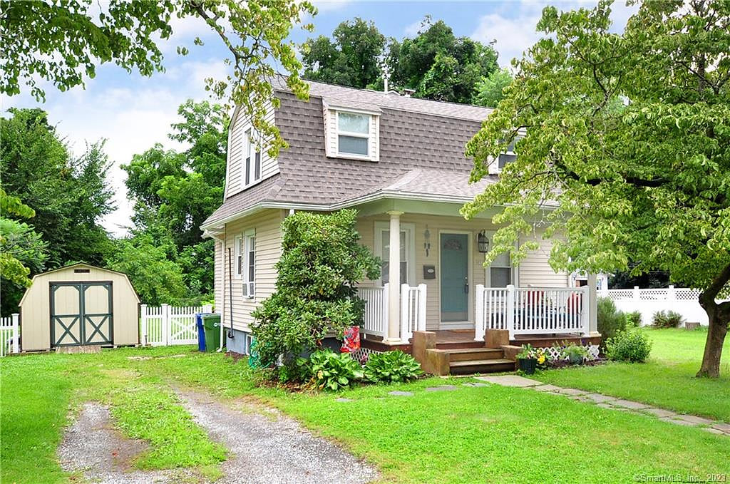 Charming cottage with covered porch, large fenced yard, and parking.