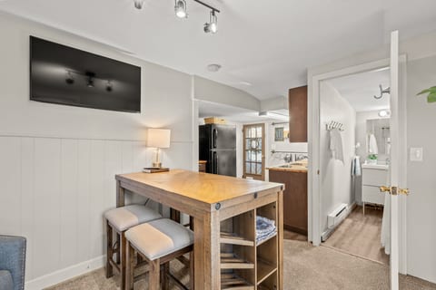 Cozy suite with kitchenette, wall-mounted TV, and adjoining bath.