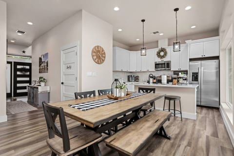 A beautiful rustic farmhouse-style dining area featuring a solid wood table and seating for six guests. Large windows and double doors open to breathtaking views, creating a bright and welcoming space to enjoy meals with family or friends.