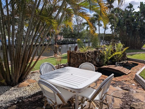 Canal-front patio with palms, pond & dock—perfect for alfresco dining