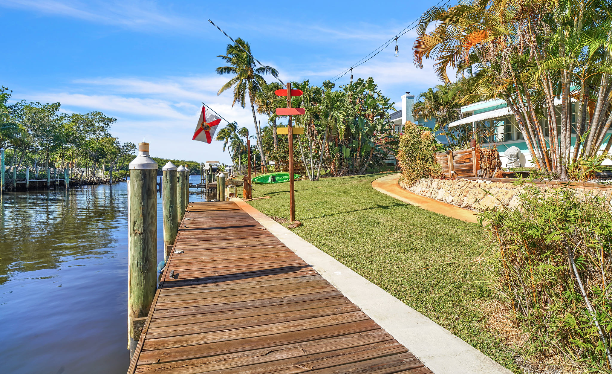 Canal-front lawn with private dock, kayaks and string-lit tropical seating.