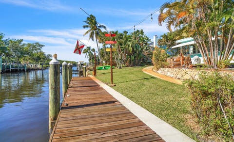 Canal-front lawn with private dock, kayaks and string-lit tropical seating.