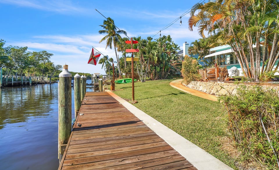 Canal-front lawn with private dock, kayaks and string-lit tropical seating.
