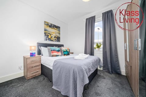 Well-lit and roomy bedroom at Klass Living Short Lets & Serviced Accommodation Airdrie, complete with a wardrobe and chest of drawers providing comfort and convenience for both business and leisure stays.