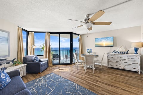 Bright beachfront living area with floor-to-ceiling windows and private balcony overlooking the Gulf