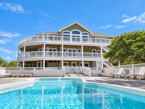 The Fitzgerald Estate illuminated at twilight — private heated pool, expansive multilevel decks, and direct oceanfront access for an unforgettable luxury retreat on the Outer Banks