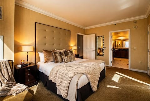 Serene King Bedroom — A plush upholstered headboard, layered bedding, warm bedside lighting, and elegant furnishings create a welcoming retreat.