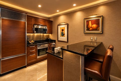Gourmet Kitchen — Warm wood cabinetry, stainless-steel appliances, a polished stone island, and an elegant two-seat dining nook.