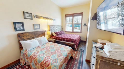 Warm, rustic bedroom with King and full beds and mountain views — comfort meets adventure.