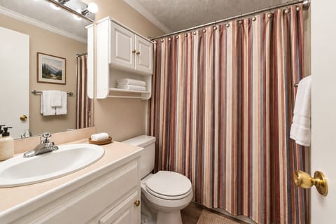 Cozy Beige Bathroom with Striped Shower Curtain. Get ready for the day in this Modern Bathroom!