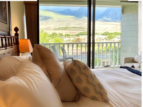 Wake to West Maui Mountains framed by floor-to-ceiling windows. Natural light floods this space, perfect for creative work with an inspiring backdrop. Premium bedding, queen mattress, wood carved bed, high quality tract blackout shade.