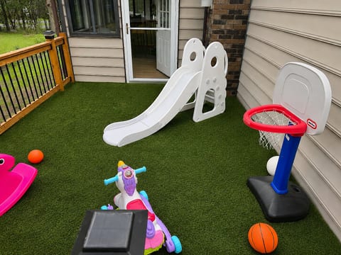 Kid-friendly deck with turf, slide, and mini basketball hoop
