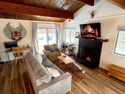 Warm, inviting living room with high wood beamed ceilings, fireplace, smart TV, and comfortable seating. Enjoy games, books, or music by the fire, or step through sliding doors to the fenced backyard. Includes a desk and monitor for remote work.