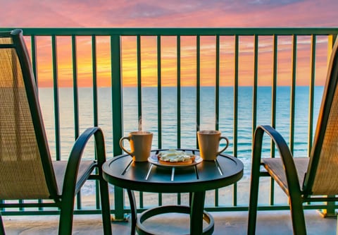 Private oceanfront balcony with cozy seating and sweeping sunset views