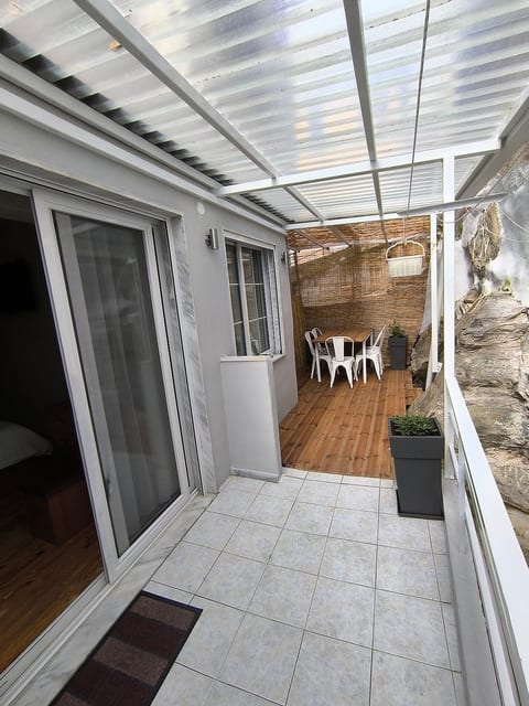 A patio with a dining table for 5 people, a shed and a canopy for shade from the Sun, in the space there is a washing machine and clothes ropes.