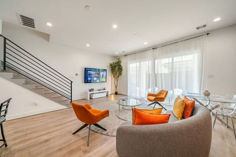 Sunlit modern lounge with smart TV, chic glass dining, and patio access.