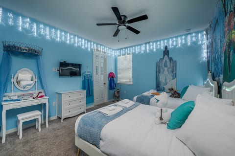 Whimsical themed bedroom with two beds, TV, vanity, and magical decor