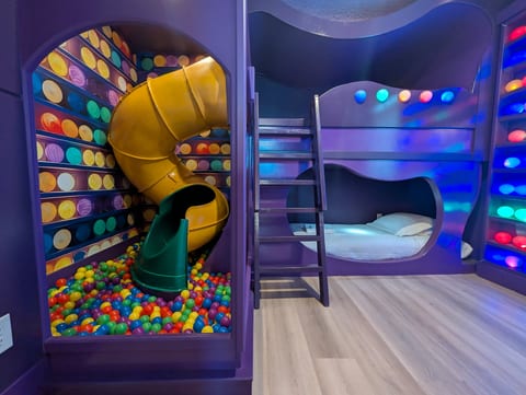 Epic kids’ room with slide, ball pit, and glowing custom bunk beds
