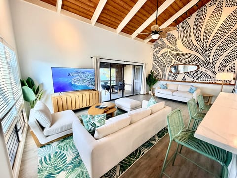 Bright vaulted lounge with statement wall, big TV, and lanai access