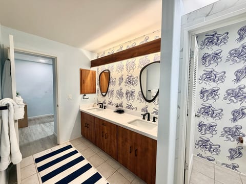 Stylish double vanity bathroom with bold coastal wallpaper