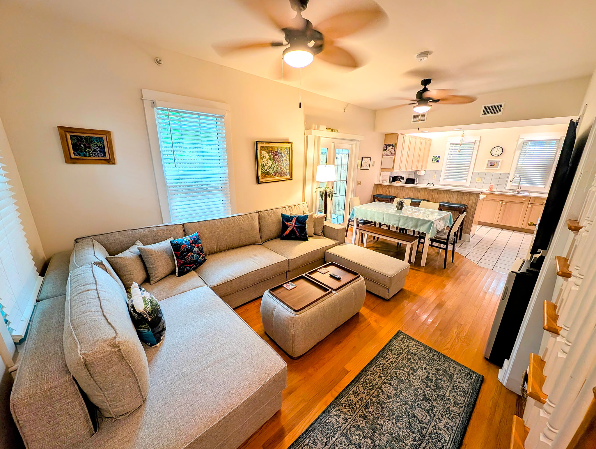 Sunny open-plan lounge with big sectional, dining table and full kitchen.